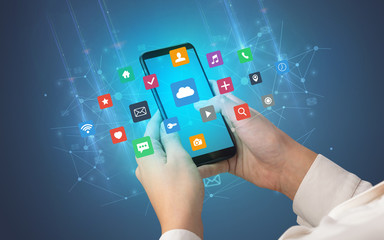 Female hand using smartphone with colorful application icons around