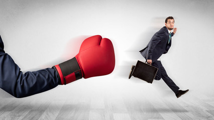 Big red boxing glove knocks out little businessman concept
