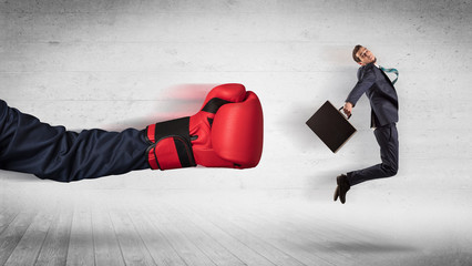 Arm with red boxing gloves hits office worker concept
