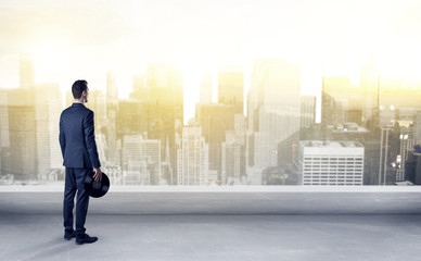 Businessman standing with his back on a roof with objects in his hand
