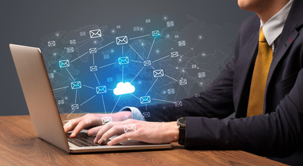 Businessman hand sending a bunch of messages on laptop with cloud computing concept
