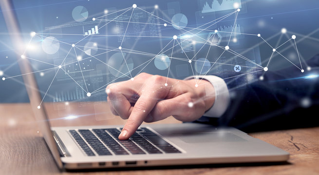 Businessman typing on laptop with linked reports charts grapghs around

