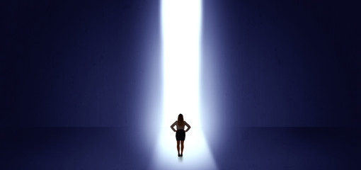 Woman standing and seeing the light at the end of a big wall
