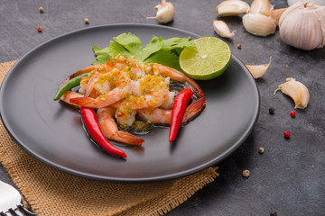 Shrimps topped with seafood sauce on black dish.