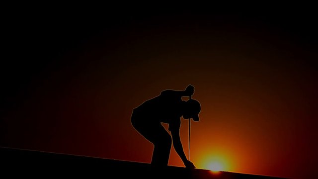 Male golfers are going to check the wind direction before a round of golf with the warm light of the setting sun