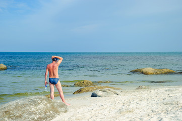 Fototapeta na wymiar Man standing on the beach looking at the sea.