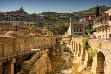 Tbilisi, Georgia, July 2, 2018. Sulfur baths in the Abanotubani district of Tbilisi, red-brick minaret of a mosque, balconied homes in Old Town, and Narikala Nariqala Fortress on the hill.