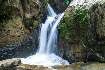 calm nature stream waterfall around the rocks in forest