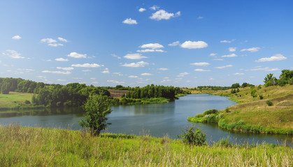 Sunny summer landscape with river,fields,green hills and beautiful clouds in blue sky.River Krasivaya in Tula region,Russia. 