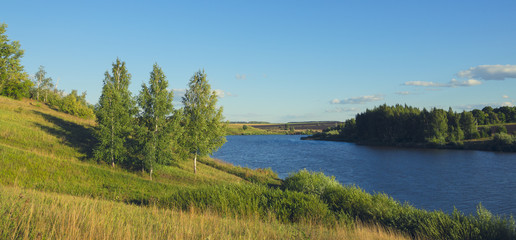 Fototapeta premium Sunny summer landscape with river,fields,green hills and beautiful clouds in blue sky.River Krasivaya in Tula region,Russia. 
