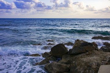 Landscape of the sundown in sea water amongst rocky beach