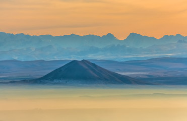 Naklejka premium Mountains in the fog, haze. The Main Caucasian Range. Multicolored background. Mountains at sunset. Winter fog.