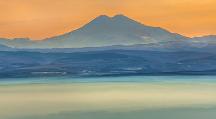 Obraz premium Mountains in the fog, haze. The Main Caucasian Range. Multicolored background. Mountains at sunset. Winter fog.