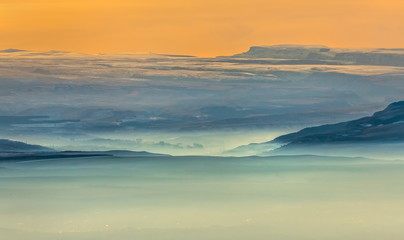 Fototapeta na wymiar Mountains in the fog, haze. The Main Caucasian Range. Multicolored background. Mountains at sunset. Winter fog.
