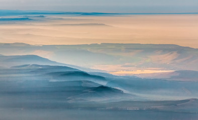 Mountains in the fog, haze. The Main Caucasian Range. Multicolored background. Mountains at sunset. Winter fog.