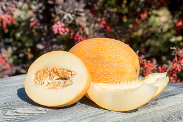 Whole and sliced melon on wooden table outdoors