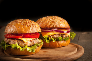 Home made hamburger with beef, onion, tomato, lettuce and cheese. Fresh burger close up on wooden rustic table with potato fries, beer and chips. Cheeseburger.