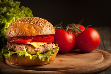 Home made hamburger with beef, onion, tomato, lettuce and cheese. Fresh burger close up on wooden rustic table with potato fries, beer and chips. Cheeseburger.