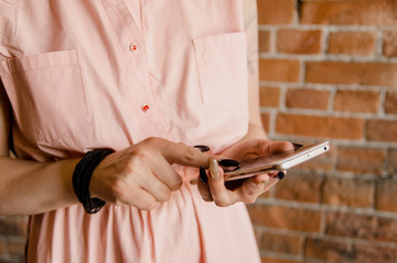 Obraz na płótnie Canvas Young girl holds smartphone on a brick wall background holds smartphone.