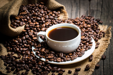 Coffee cup and beans on a rustic background. Coffee Espresso and a piece of cake with a curl. Cup of Coffee and coffee beans on table.