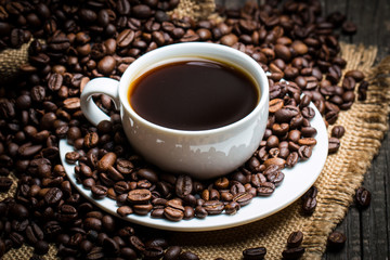 Coffee cup and beans on a rustic background. Coffee Espresso and a piece of cake with a curl. Cup of Coffee and coffee beans on table.