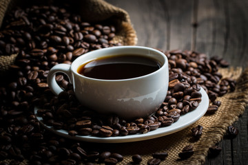 Coffee cup and beans on a rustic background. Coffee Espresso and a piece of cake with a curl. Cup of Coffee and coffee beans on table.