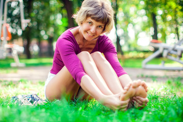 Young woman doing massage after workout in the park. Sport, medicine and people concept © Aleksej
