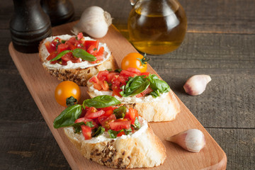 Italian tomato and cheese bruschetta. Tapas, antipasti with chopped vegetables, herbs and oil on grilled ciabatta and baguette bread.