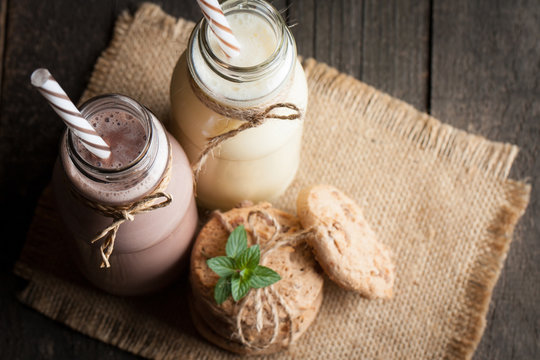 Photo of fresh Made Chocolate Banana Smoothie on a wooden table with cookies, banana and coconut. Milkshake. Protein diet. Healthy food concept. Drink, coffee beans, chocolate.