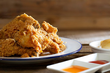 Fried chicken in white dish with souce and mash potato on wooden table