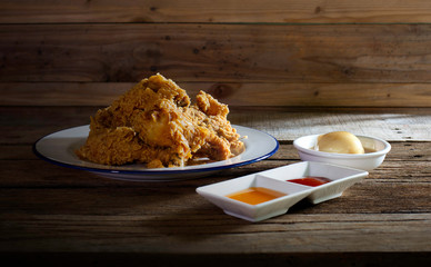 Fried chicken in white dish with souce and mash potato on wooden table still life food