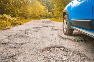 Fototapeta na wymiar car tire and cracked damaged road in the autumn forest