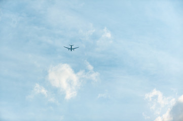 Zweistrahliger Düsenjet fliegt in leicht bewölkten blauen Himmel