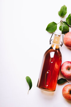 Apple vinegar in bottle on white wooden table with apples and leaves. Rustic style. Top view, copy space.