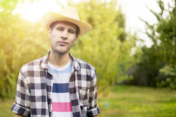 young male happy smiling farmer in hat and casual shirt in countryside natural farm a