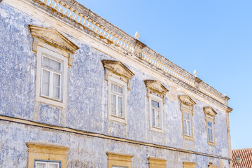 Facade of a faded painted building in Portugal with roof top balustrade