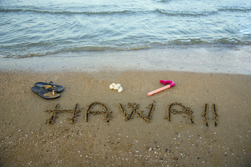 Hawaii written on the sand with snorkel an beach sleepers