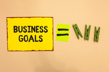Word writing text Business Goals. Business concept for Expectation to accomplish over a specific period of time Yellow piece paper reminder equal sign several clothespins sending message
