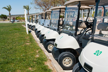 Buggies parked by the clubhouse in a golf course with green grass and palm trees on the Costa Blanca in Spain