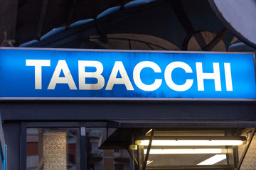 Blue signage of a Tabacchi, Italian for Tobacco shop, on a black background. Also called a tobacco shop, a tobacconist's shop or a smoke shop, it is a retailer of tobacco products