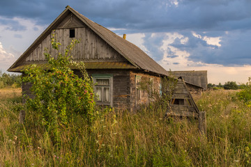 Countryside in Belarus, highr grass and old houses in the village bacground dramatic sky