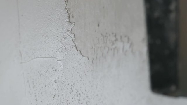 Slow motion handheld shot of worker applying putty on the wall