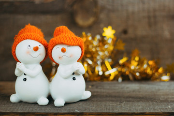 cute ceramic toy pair  snowmen in hats on festive background