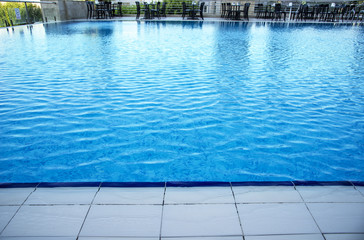 Obraz premium Chairs and tables next to a swimming pool. Luxury vacation concept