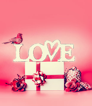 Word  LOVE with white gift box , red ribbon , heart and decoration , front view. Festive layout for greeting card
