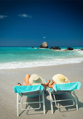 Couple on sunbeds relaxing at the beach in Lefkada
