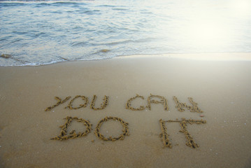 You can do it. Motivational inspirational message concept written on the sand of beach