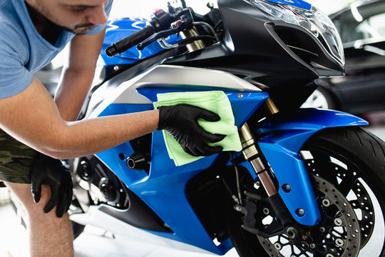 Fototapeta A man cleaning motorcycle with cloth. Selective focus.