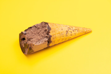 chocolate flavor ice cream cone with some bites on a yellow background