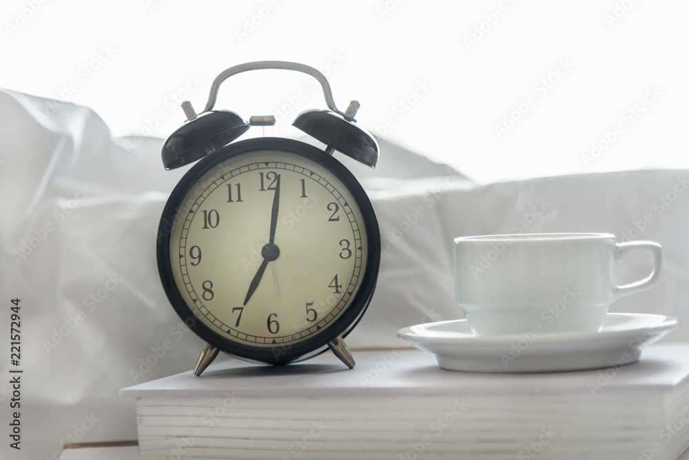 Wall mural alarm clock with book on bed in morning with sun light